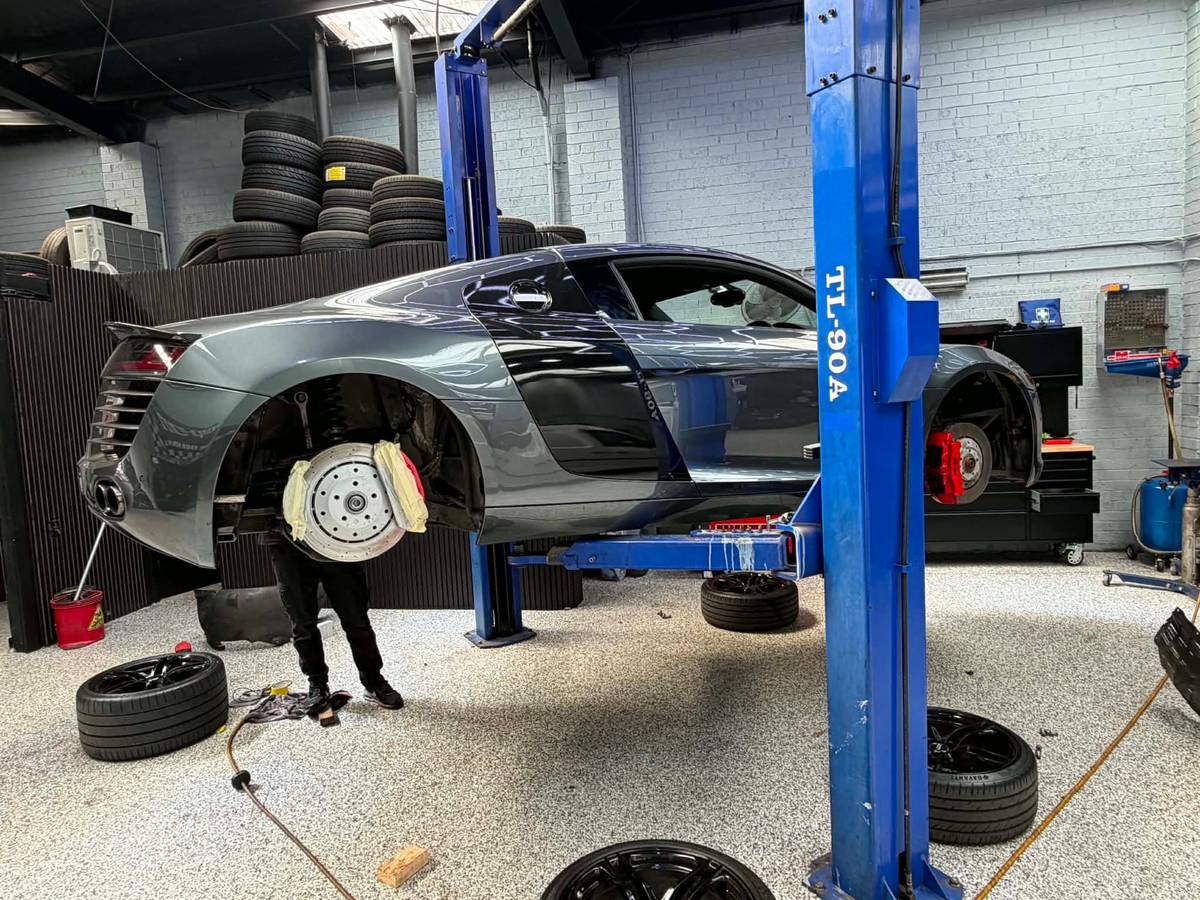 An Audi R8 up on the hoist mid-service at Darwish Motors, wheels off, with stacks of tyres in the background